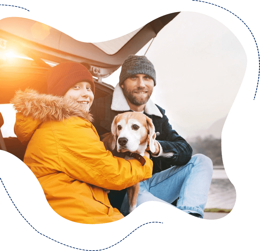 A man and woman sitting on the back of a car with their dog.